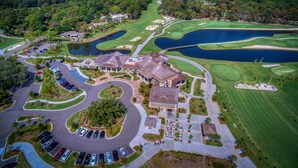 An aerial view of a golf course with a clubhouse, parking areas, and surrounding greenery. - New Inventory! Updated Kitchens and Baths 2 BR Bikes & Beach Gear included (Hilton Head Island)