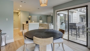 A modern dining area with a round table and chairs, a kitchen in the background, and a sliding glass door leading to an outdoor patio. - New Inventory! Updated Kitchens and Baths 2 BR Bikes & Beach Gear included (Hilton Head Island)