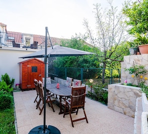 An outdoor patio with a table and chairs, a wooden shed, and a stone wall. - Holiday Home Avantgarde (Dubrovnik)