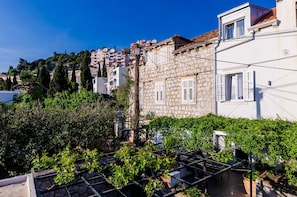 A residential area with stone buildings, a rooftop garden, and a view of a hillside with other buildings. - Holiday Home Avantgarde (Dubrovnik)