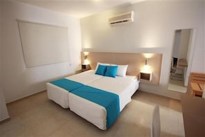 Hotellihuone, jossa on parivuode, yöpöytälamput, suuri peili ja puinen yöpöytä.