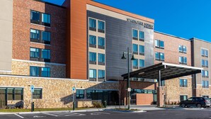 A modern hotel building with multiple floors, large windows, and a covered entrance area.