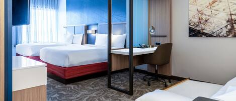 A hotel room with two beds, a desk, a chair, and a TV.