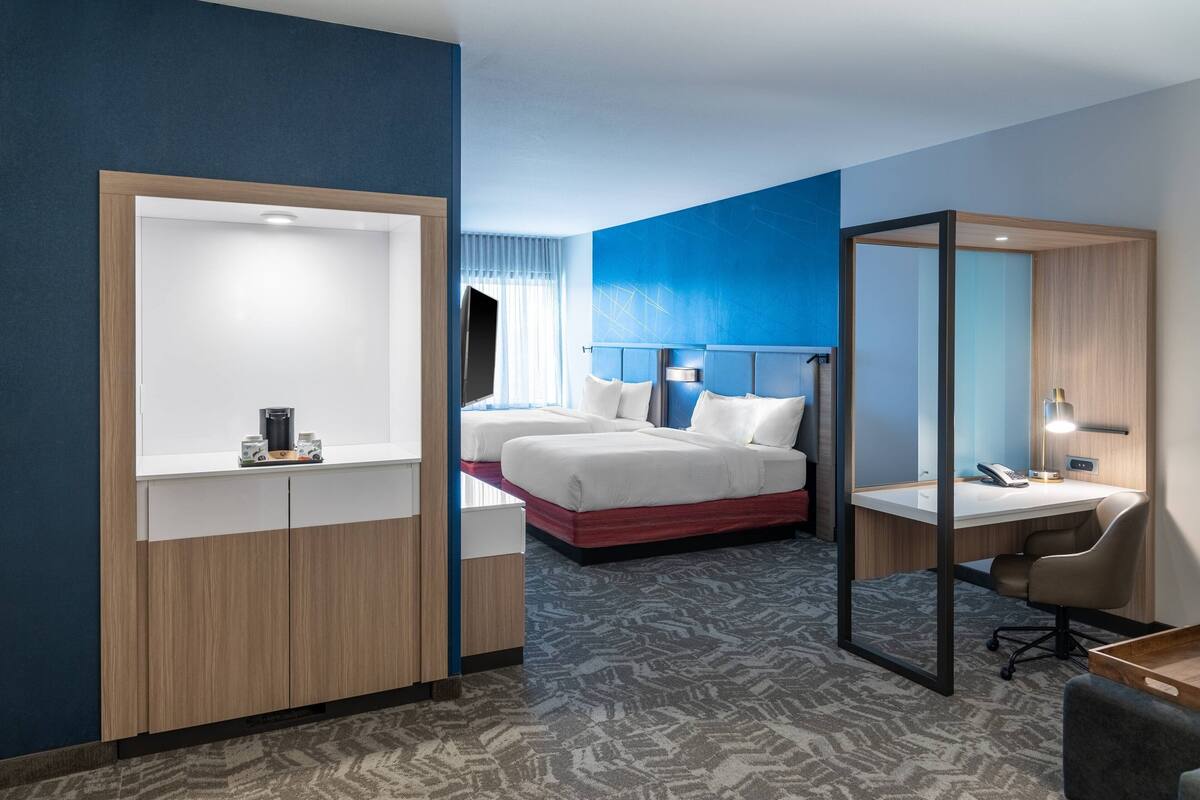 A hotel room with a bed, a desk, a chair, and a wardrobe.