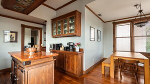 Une cuisine avec des meubles de rangement en bois, un plan de travail en bois et une table à manger avec une chaise.