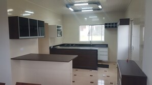 A kitchen with a central island, cabinets, a stove, and a window. - Sítio Santa Filomena São Roque/SP (São Roque)