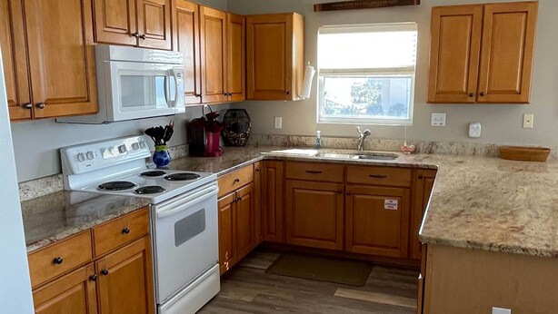 A kitchen with wooden cabinets, a microwave, stove, and a sink.