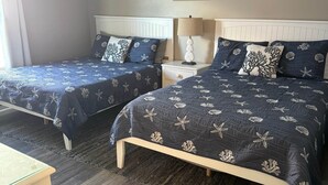 Two twin beds with matching headboards and footboards, a bedside table with a lamp, and a small table in the foreground.