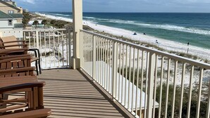 A balcony with a view of the beach and ocean.