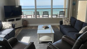 Ein Wohnzimmer mit Fernseher, Sofa, Couchtisch und Meerblick.