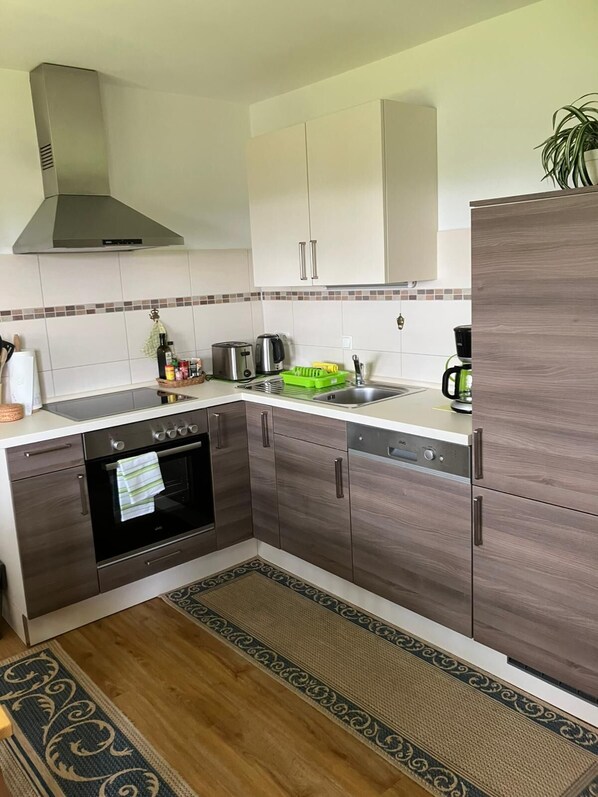 Eine moderne Küche mit dunklen Holzschränken, einer Edelstahl-Dunstabzugshaube und einer gefliesten Spritzschutzwand.