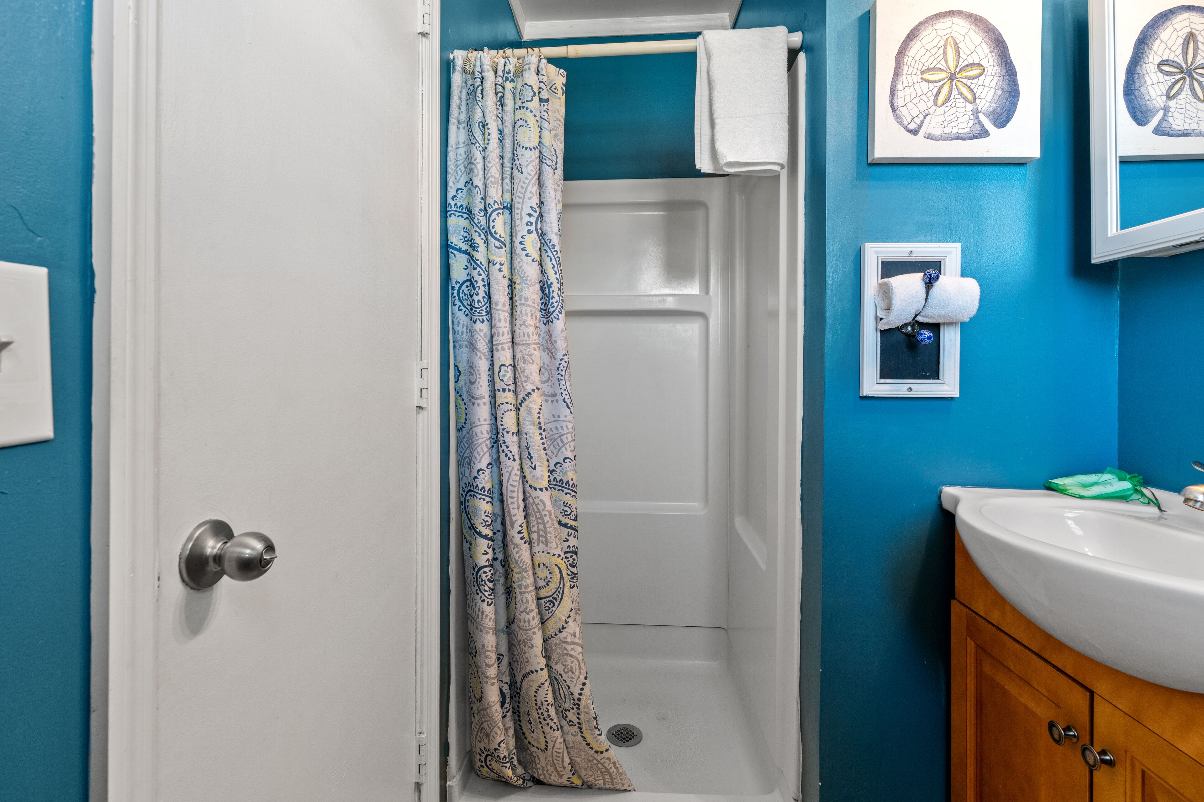 A bathroom with a shower, a sink, and a towel rack.