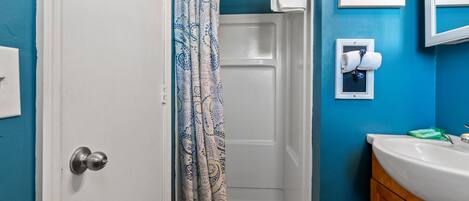 A bathroom with a shower, a sink, and a towel rack.