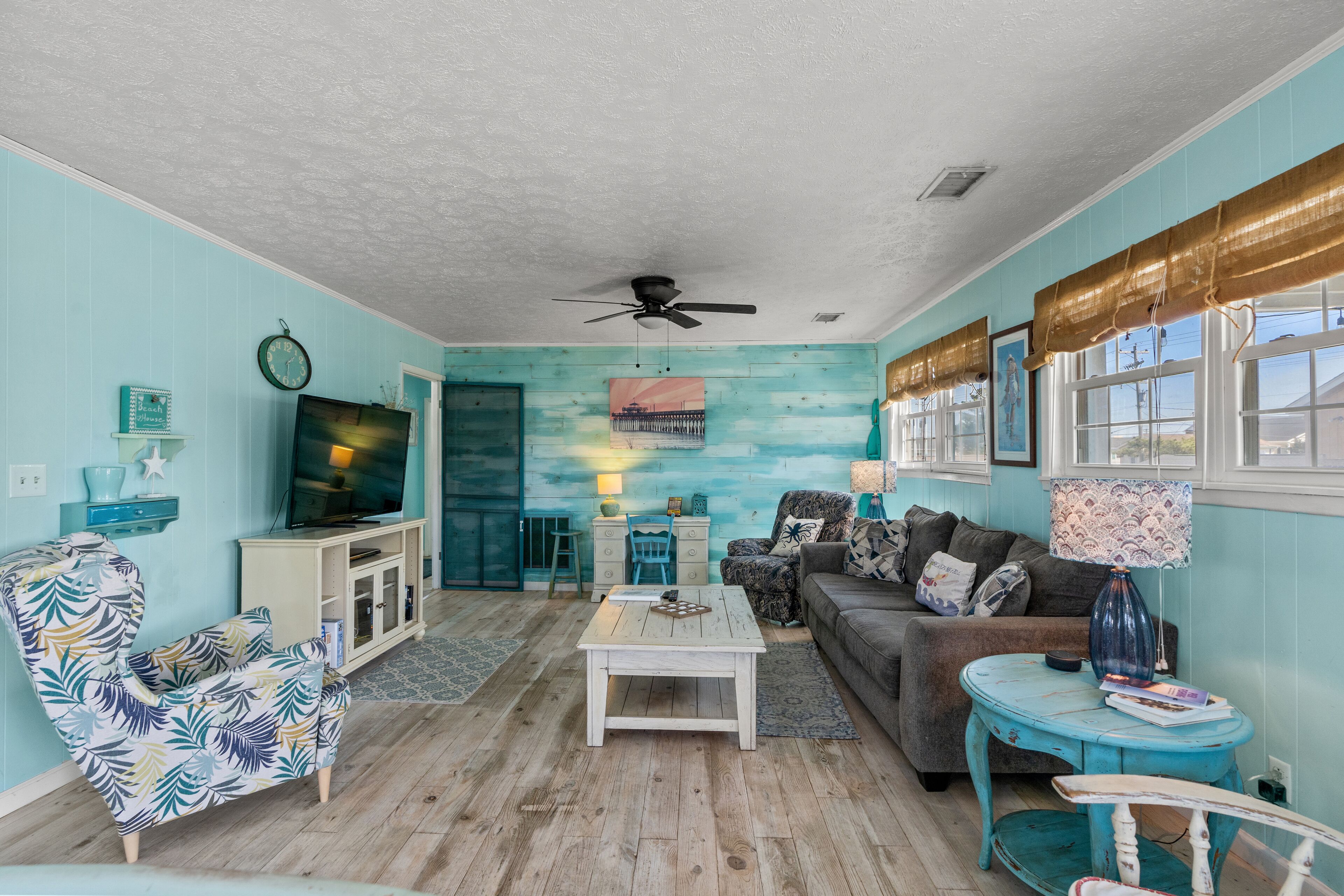 A living room with a television, sofa, coffee table, and a ceiling fan.