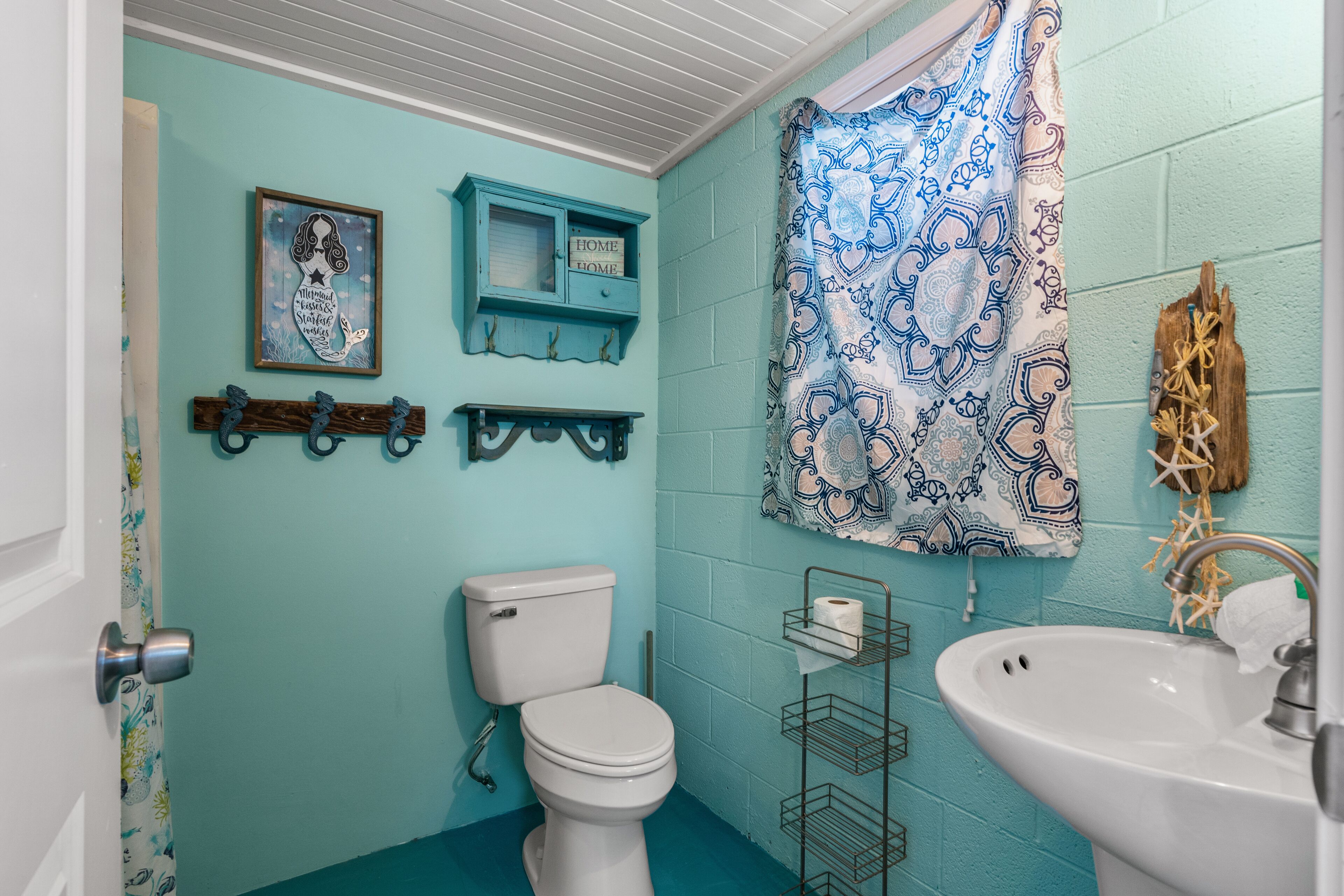 A bathroom with a toilet, sink, and a blue wall.