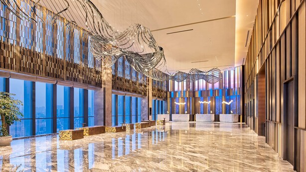 Un hall d’entrée spacieux doté d’un sol en marbre poli, de grandes fenêtres offrant une vue sur la ville et d’un design de plafond moderne.