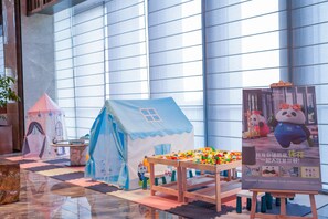 Zona de juegos infantiles con una carpa, una mesa de juegos y juguetes.