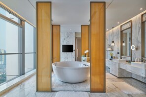 Un baño moderno con una bañera independiente, suelo de mármol, detalles de madera y un espejo grande.