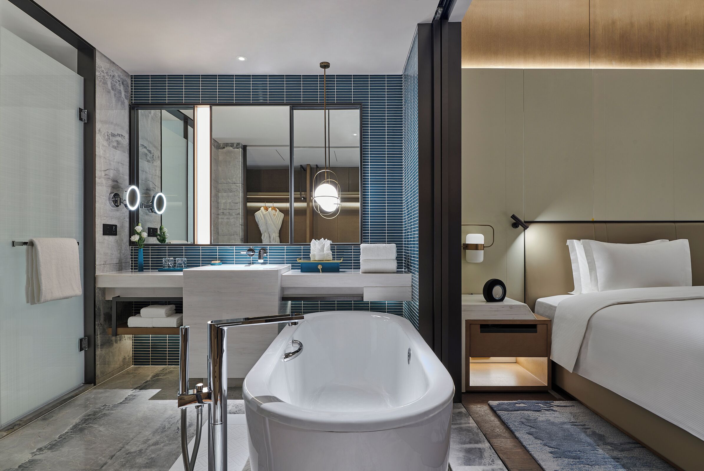 Une salle de bain d’hôtel moderne avec une baignoire sur pieds, un grand miroir et un meuble-lavabo doté d’un porte-serviettes.