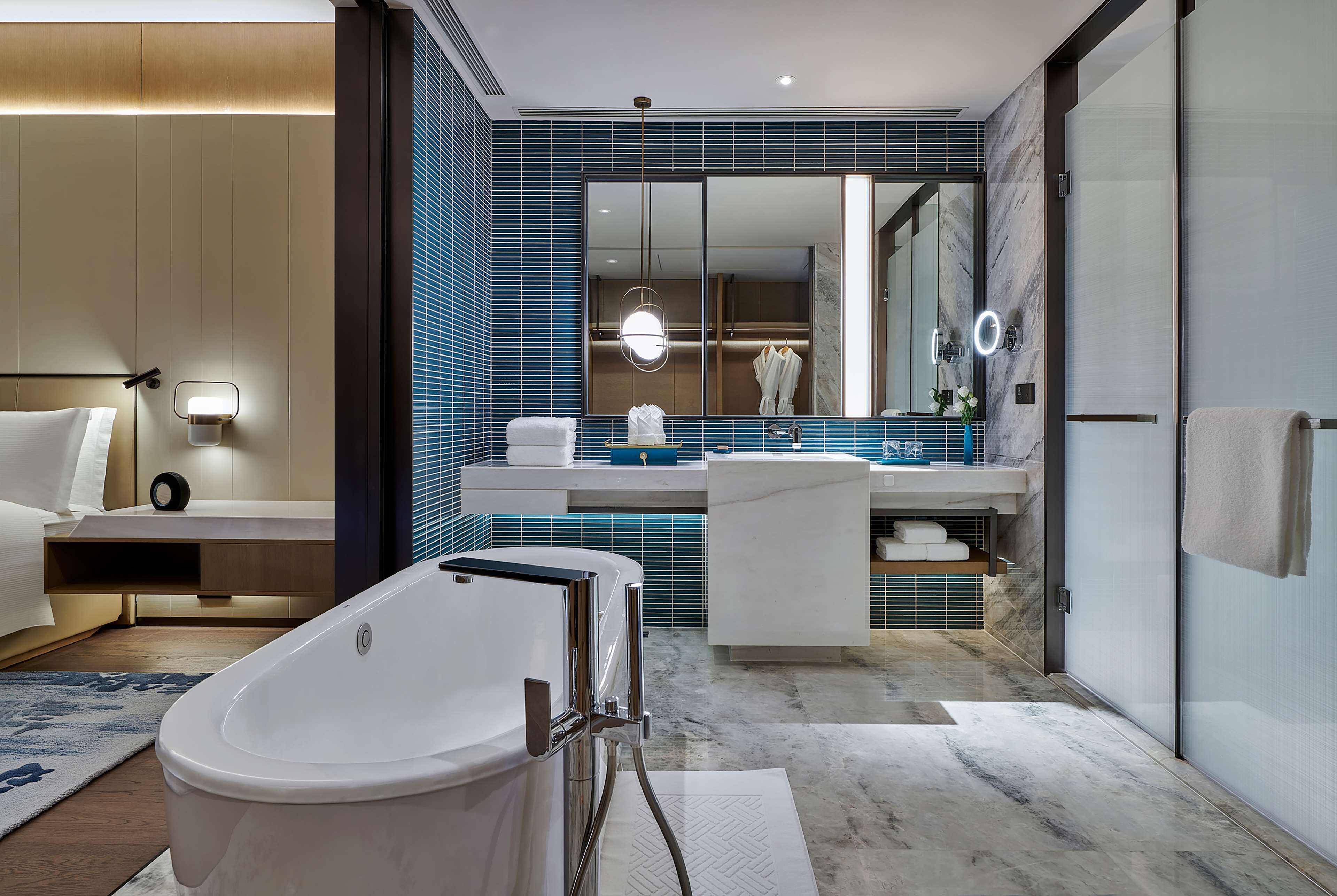 Ein modernes Badezimmer mit freistehender Badewanne, einem großen Spiegel und einem Waschtisch mit Spüle und Handtuchhalter.