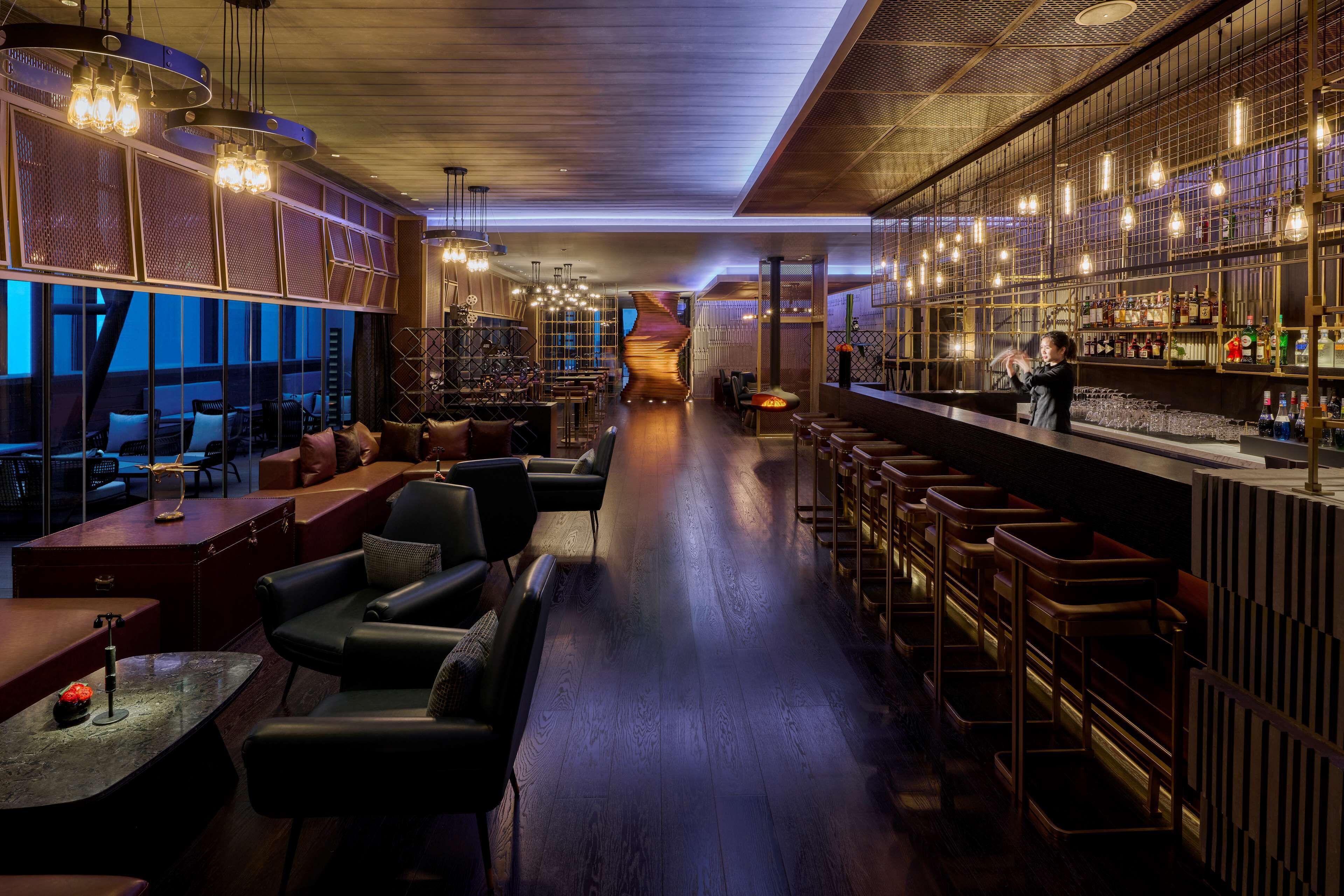 A bar area with seating, a bar counter, and a variety of bottles and glasses.