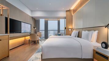 Habitación de hotel moderna con una cama grande, un escritorio, un televisor de pantalla plana y vistas a la ciudad.