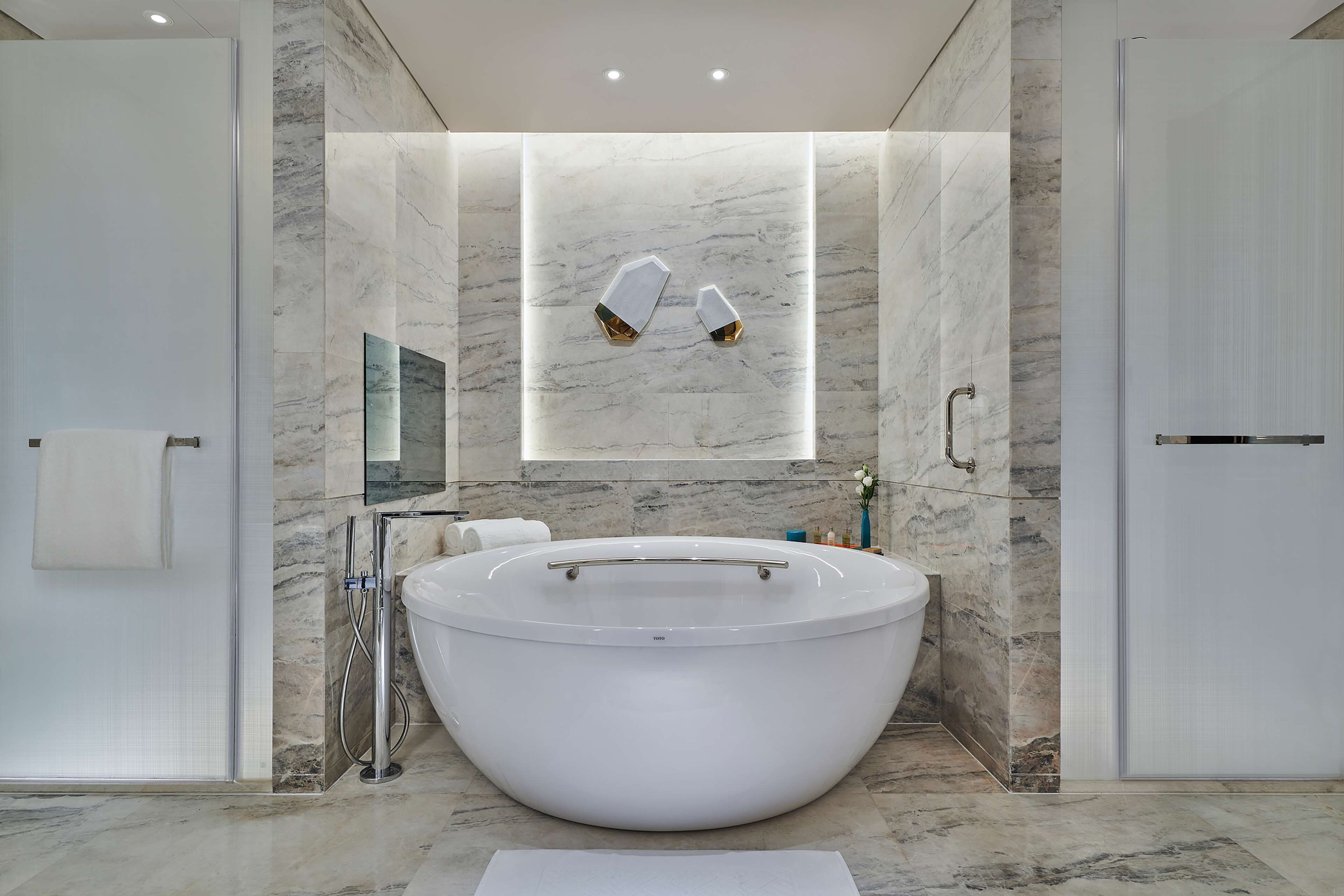 Een aparte badkuip en douche, een regendouche, designer toiletartikelen
