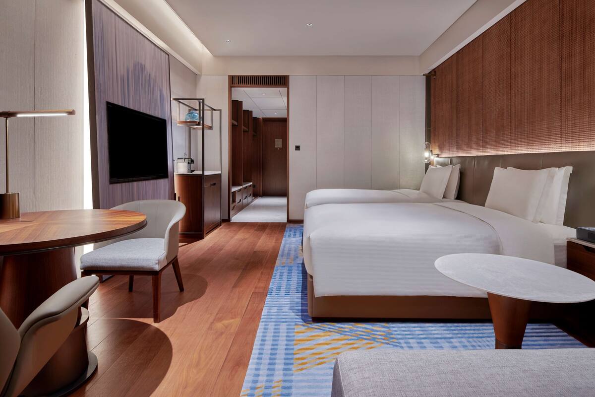 Une chambre d’hôtel moderne dotée d’un grand lit, d’un bureau, d’une chaise, d’une télévision et d’un dressing.