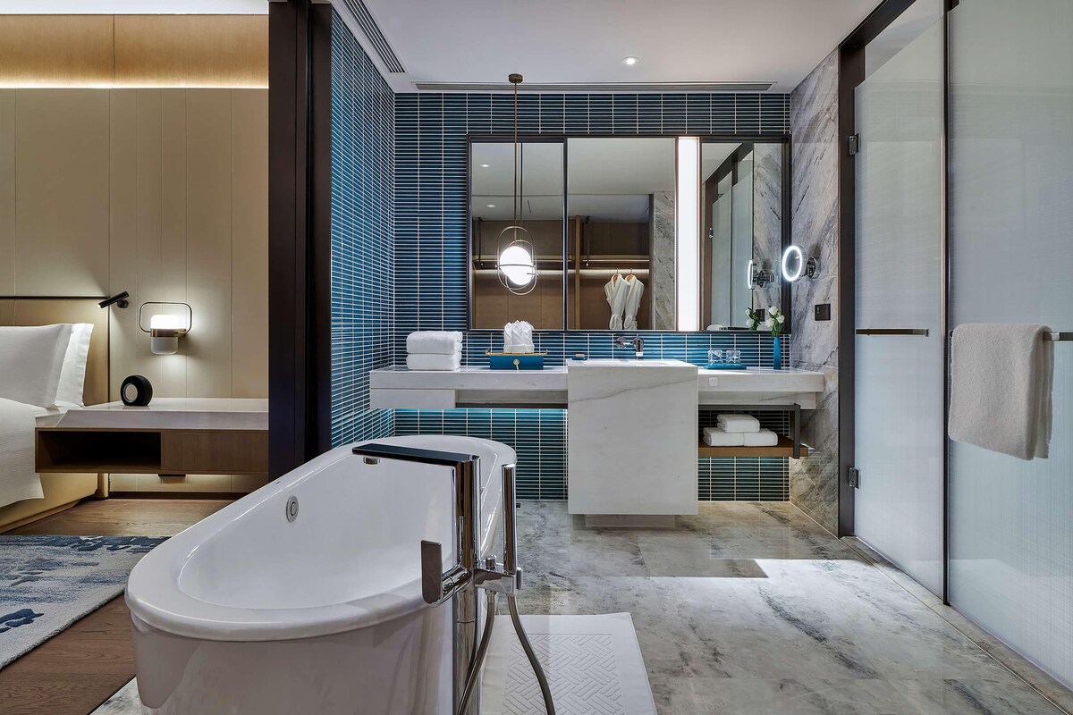 Une salle de bain moderne avec une baignoire sur pieds, un grand miroir et un meuble-lavabo doté d’un évier et d’un porte-serviettes.