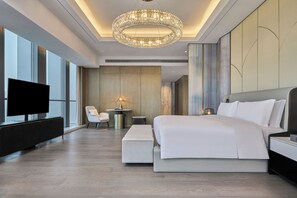 Een moderne hotelkamer met een groot bed, een televisie, een bureau met lamp en uitzicht op de stad.