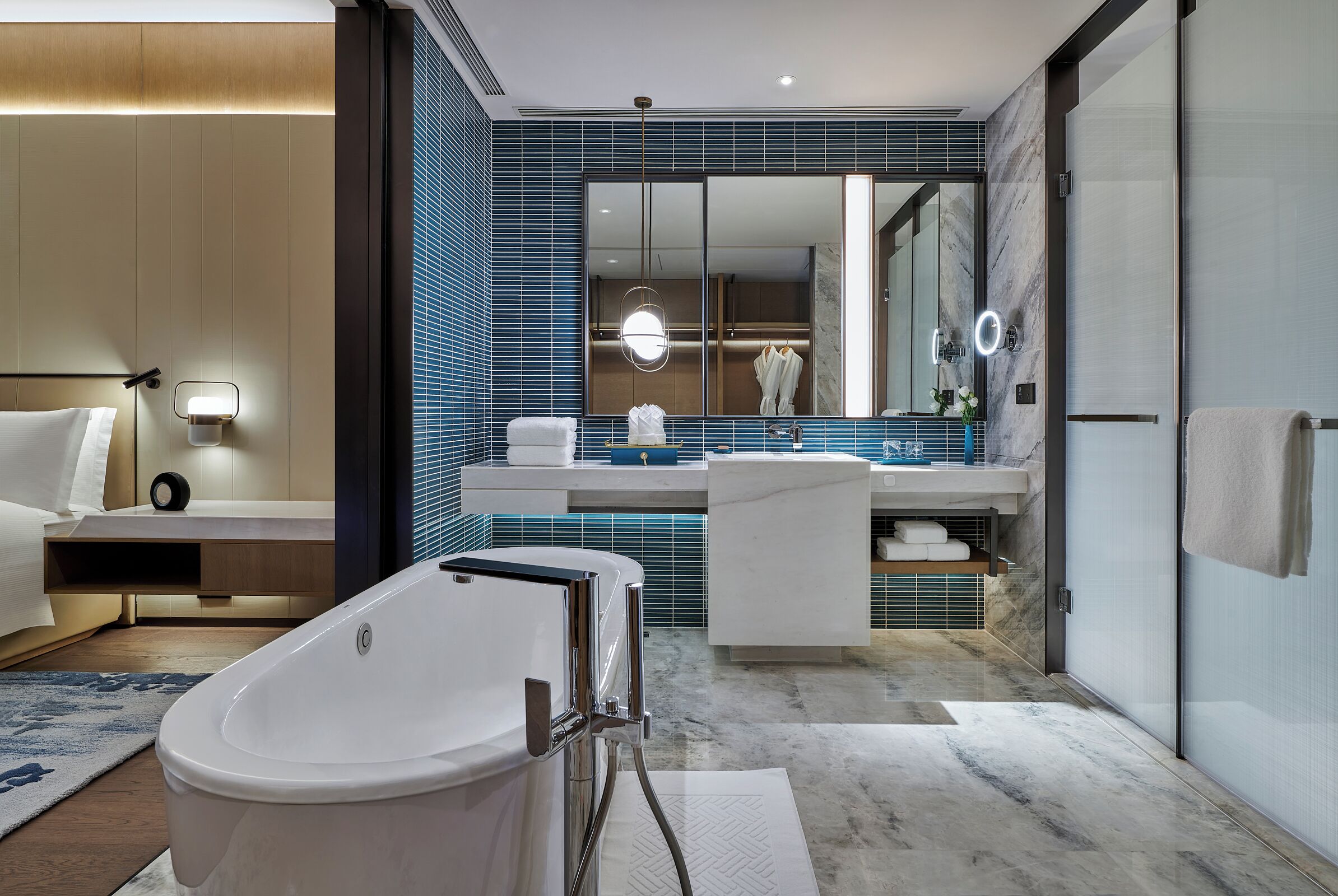 A modern bathroom with a freestanding bathtub, a large mirror, and a vanity with a sink and towel rack.
