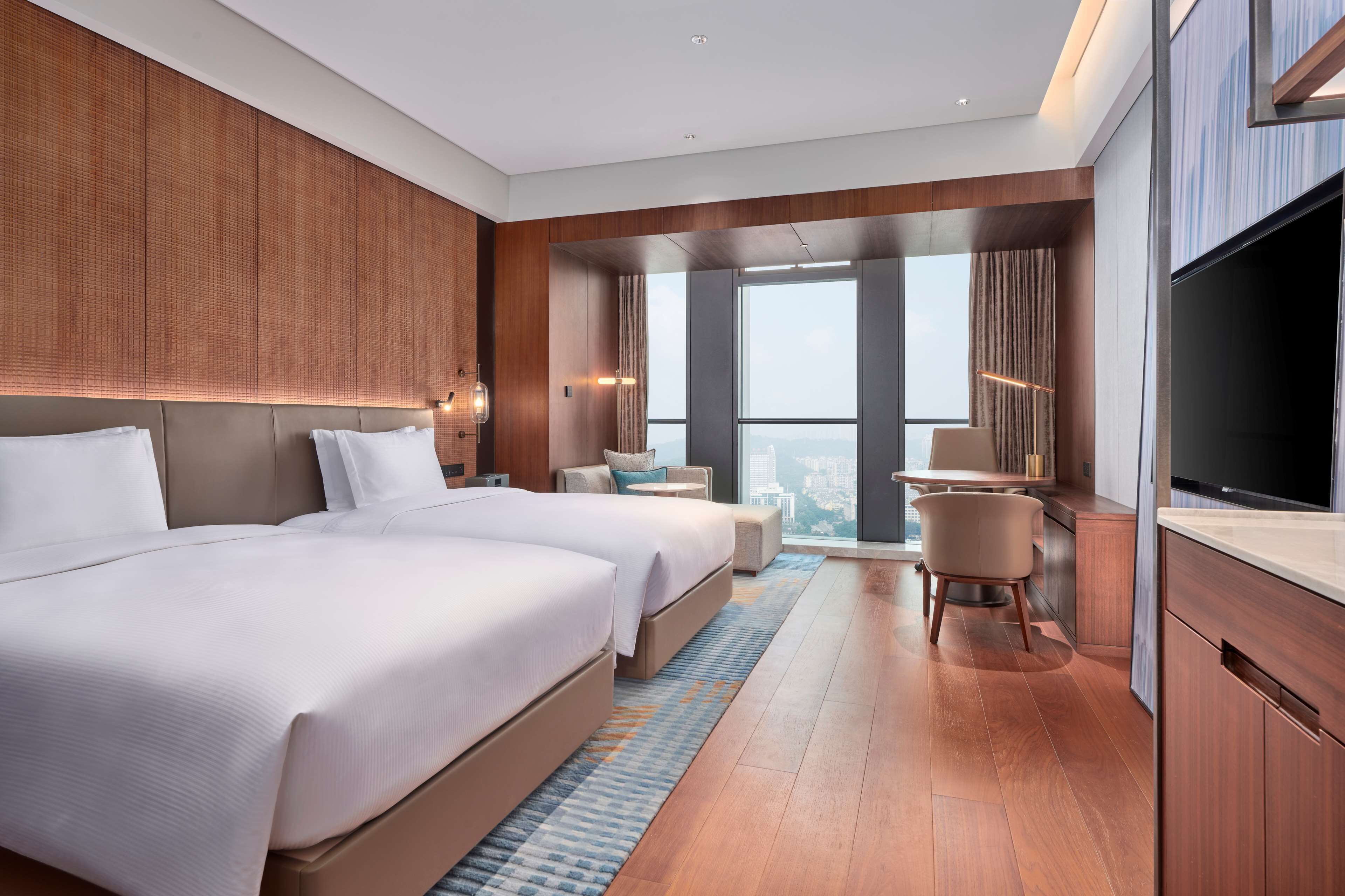 A modern hotel room with a large bed, a desk, and a TV.
