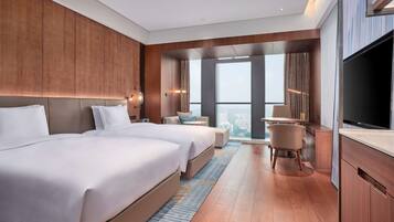 A modern hotel room with a large bed, a desk, and a TV.