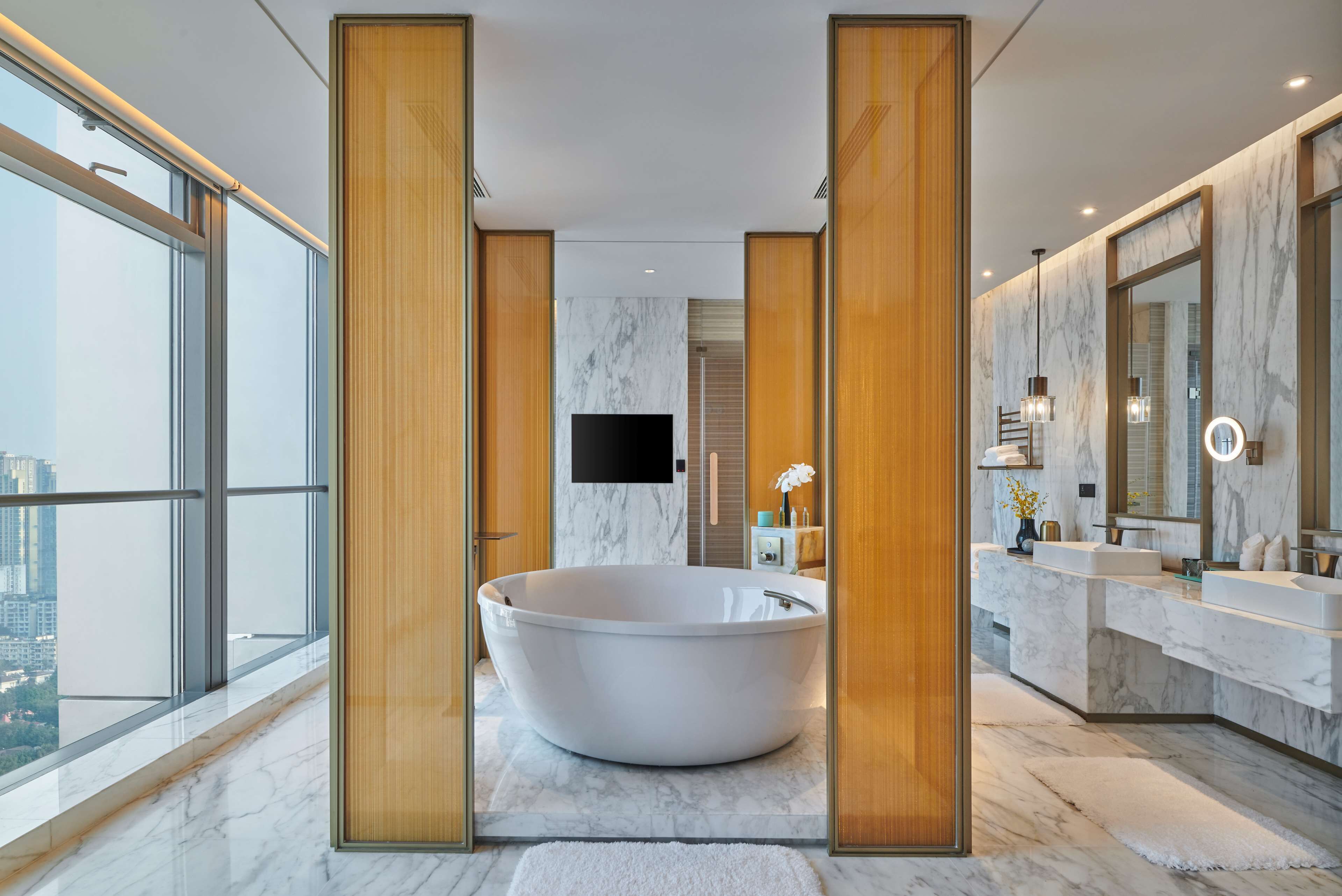 Un baño moderno con una bañera independiente, suelo de mármol y un espejo grande.