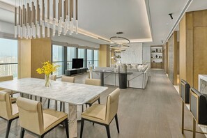 Una cocina moderna con una isla central, un comedor con mesa de mármol y vistas a la ciudad.