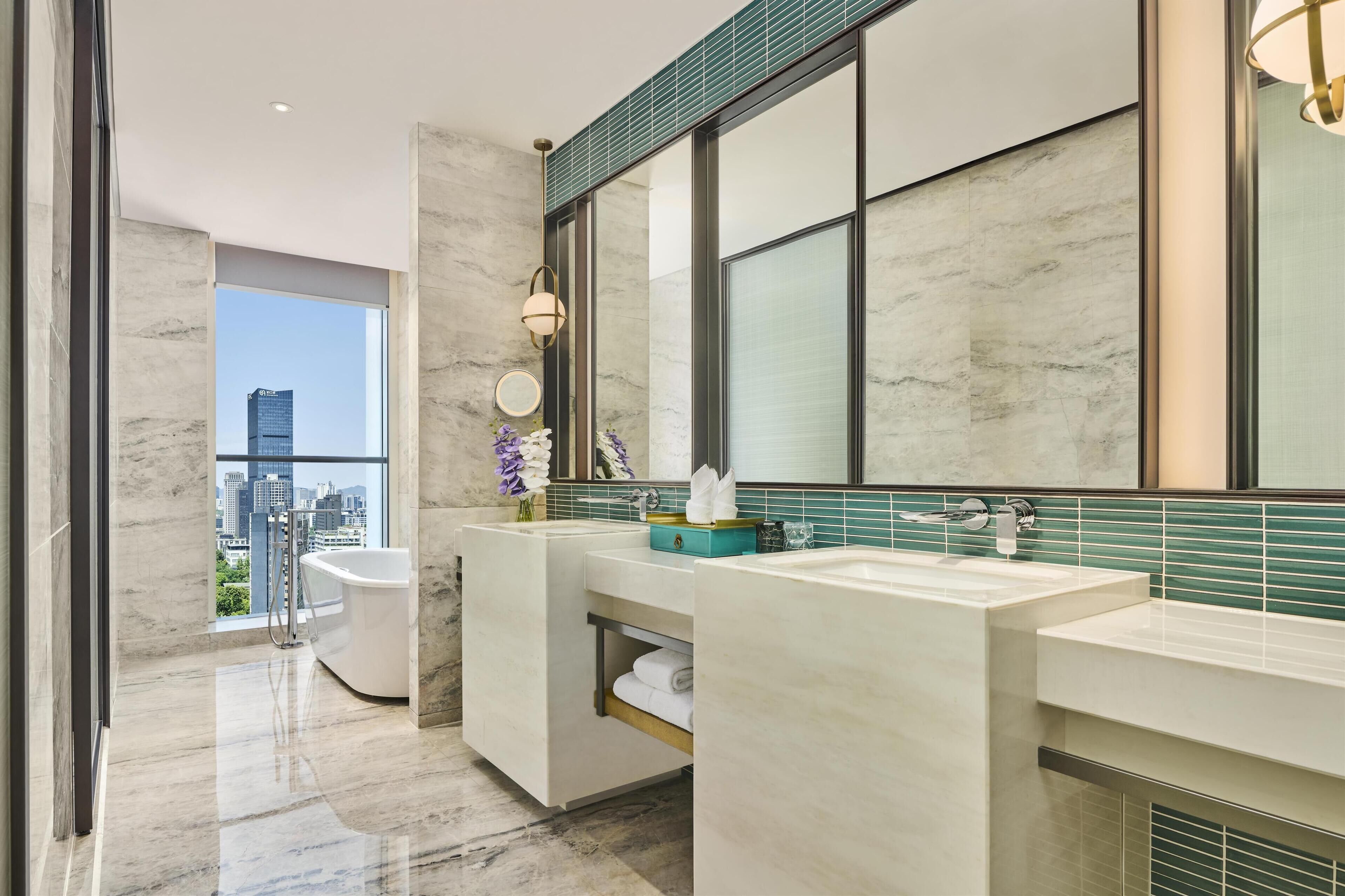 A modern bathroom with two sinks, a bathtub, and a large mirror.