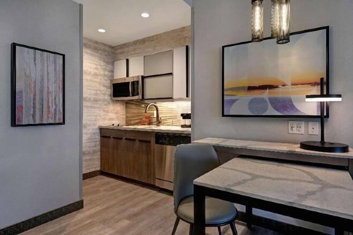 A modern kitchen with a built-in microwave, stainless steel appliances, and a dining area with a table and chairs.