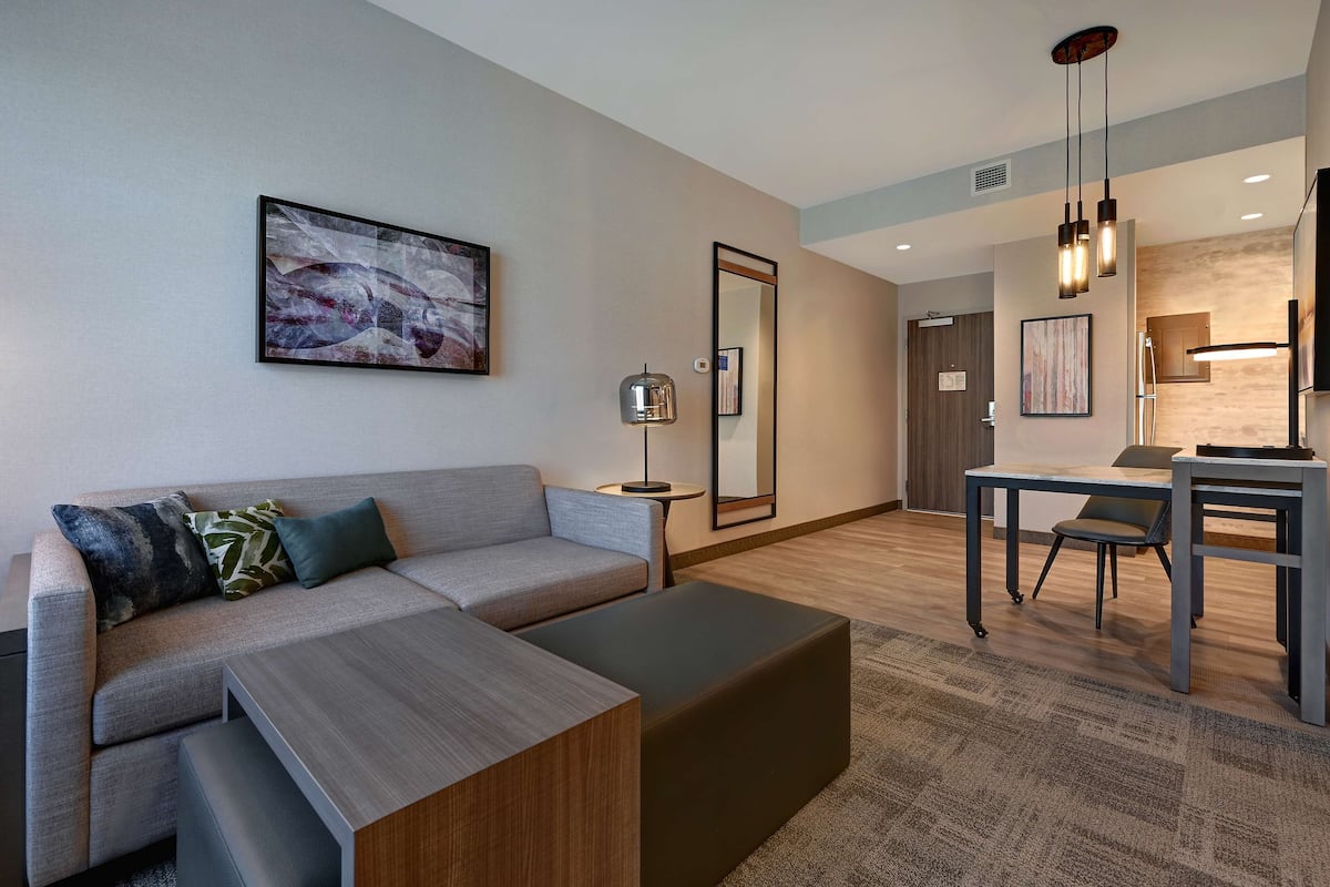 A modern living room with a sectional sofa, a coffee table, and a dining area with a table and chairs.