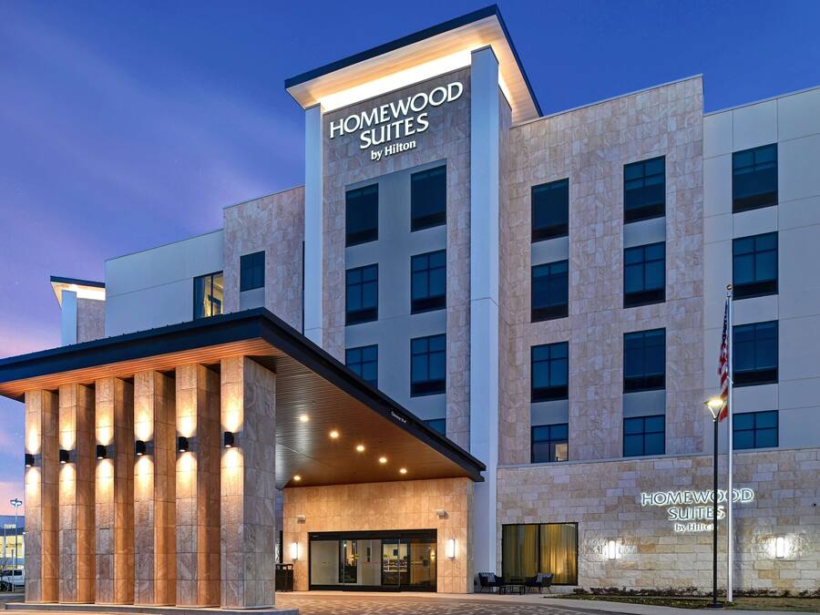 Un hotel moderno con una entrada destacada, amplias ventanas y fachada de piedra.