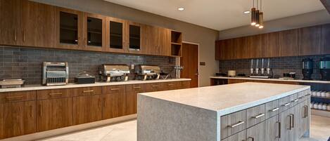 A modern kitchen with wooden cabinets, a marble island, and built-in appliances.