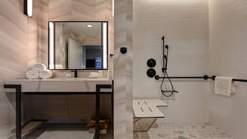 Un baño moderno con un espejo grande, un lavamanos con toallero y una zona de ducha con barra para toallas.