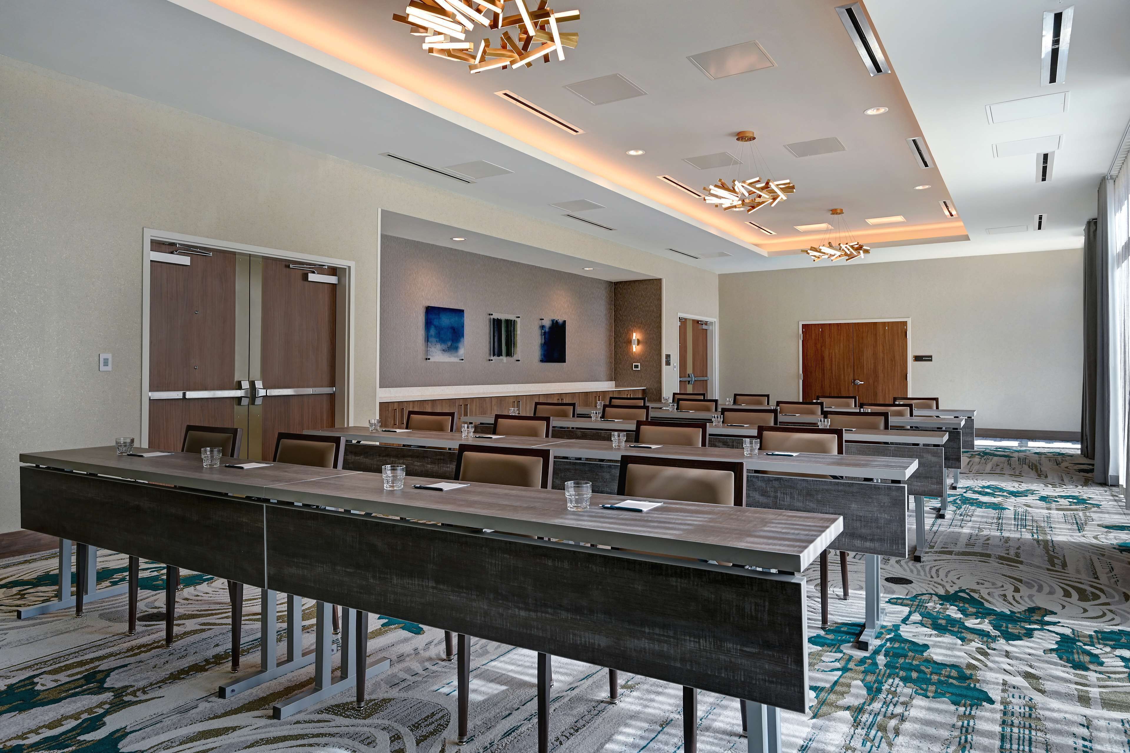 Une salle de conférence avec de longues tables, des chaises et un tapis à motifs.