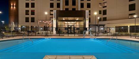 Ett hotell med en swimmingpool, en överbyggd entré och en modern fasad.