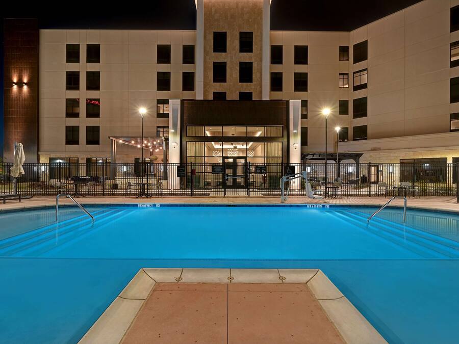 A hotel with a swimming pool, a covered entrance, and a modern building facade.
