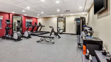 A gym with treadmills, elliptical machines, a bench press, and free weights.