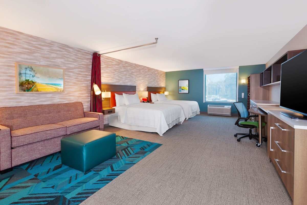 Une chambre d’hôtel avec un lit, un canapé, un bureau et une télévision.