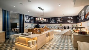 Interior moderno de café com balcão central, área de estar e arte motivacional nas paredes.