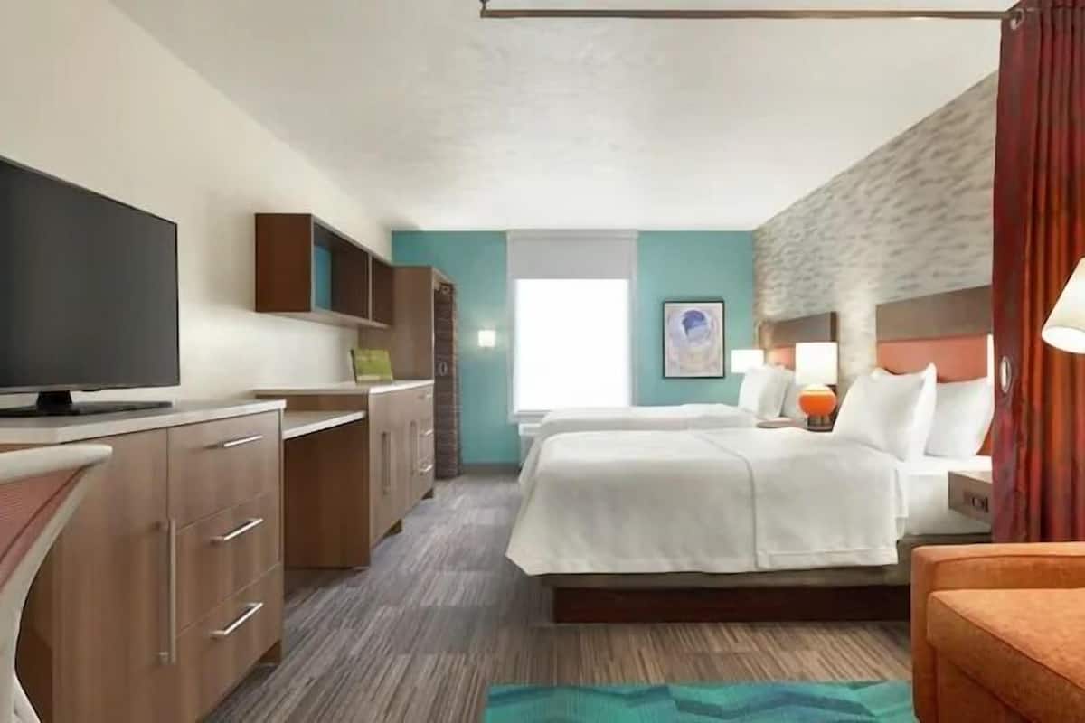 A hotel room with a bed, a TV, a desk, and a chair.