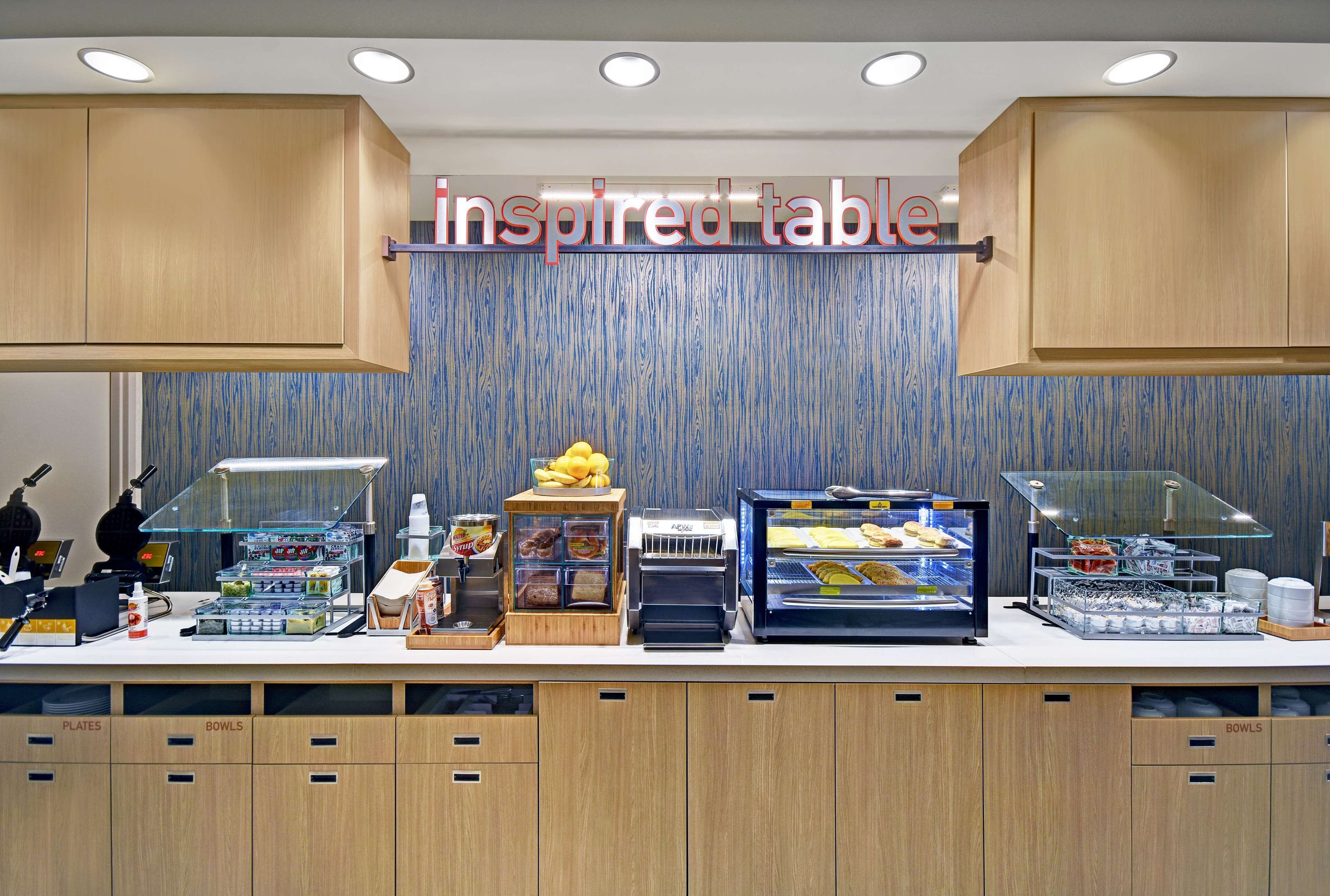 A self-service breakfast area with a variety of food options, including a display case with pastries and a coffee station.