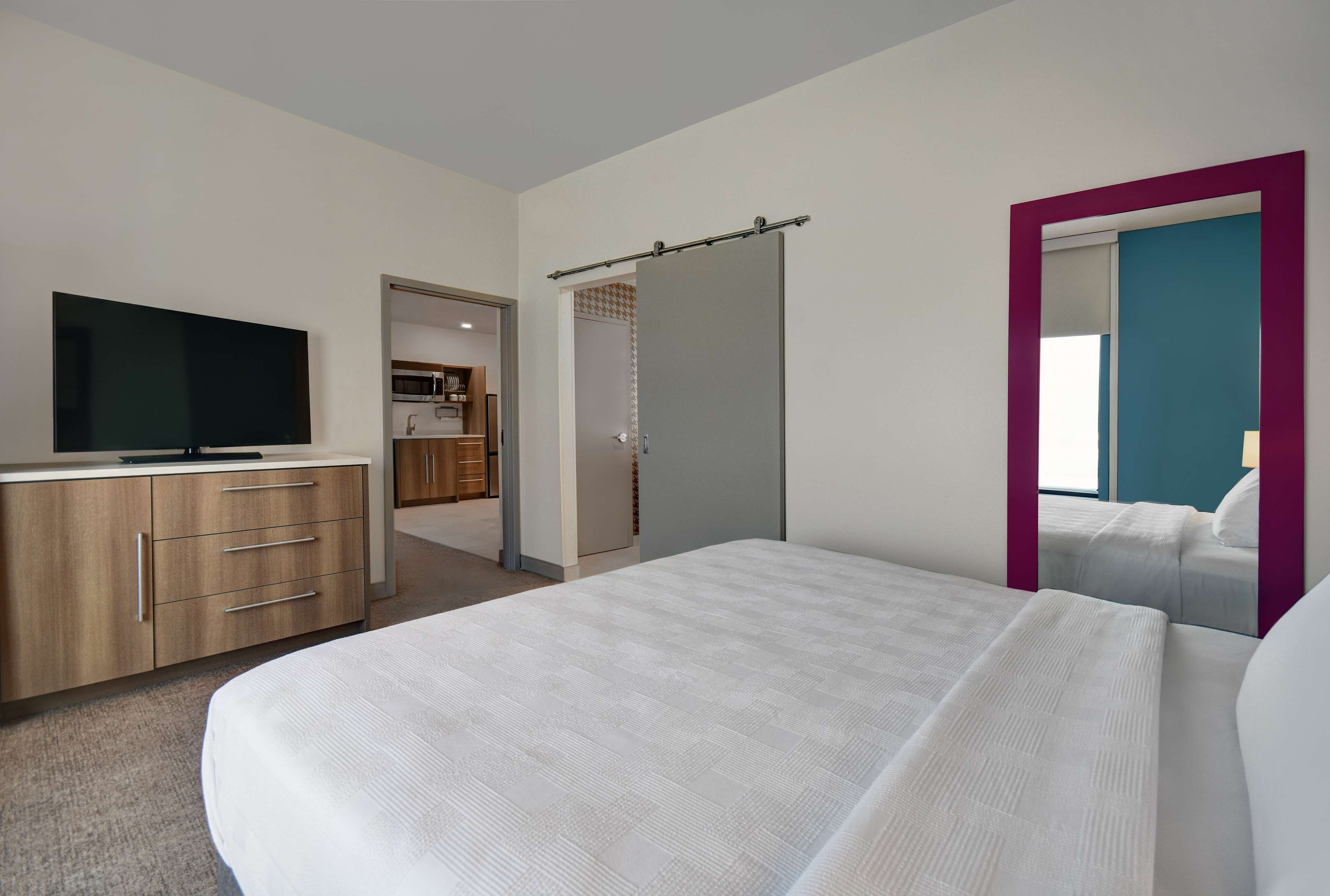 Une chambre d’hôtel avec un lit, une télévision, une armoire et une salle de bain visible à travers une porte ouverte.